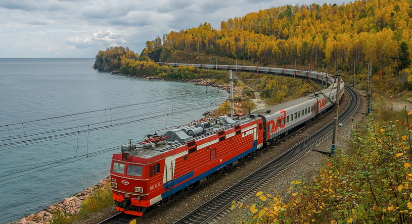 Поезд едет вдоль берега озера Байкал осенью
