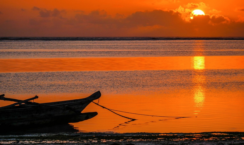 Рыбацкая лодка на берегу Индийского океана, солнце заходит, красный закат