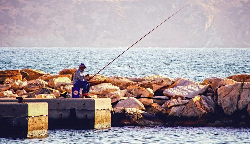 Лето, каменный берег, рыбак с удочкой. рыбалка
